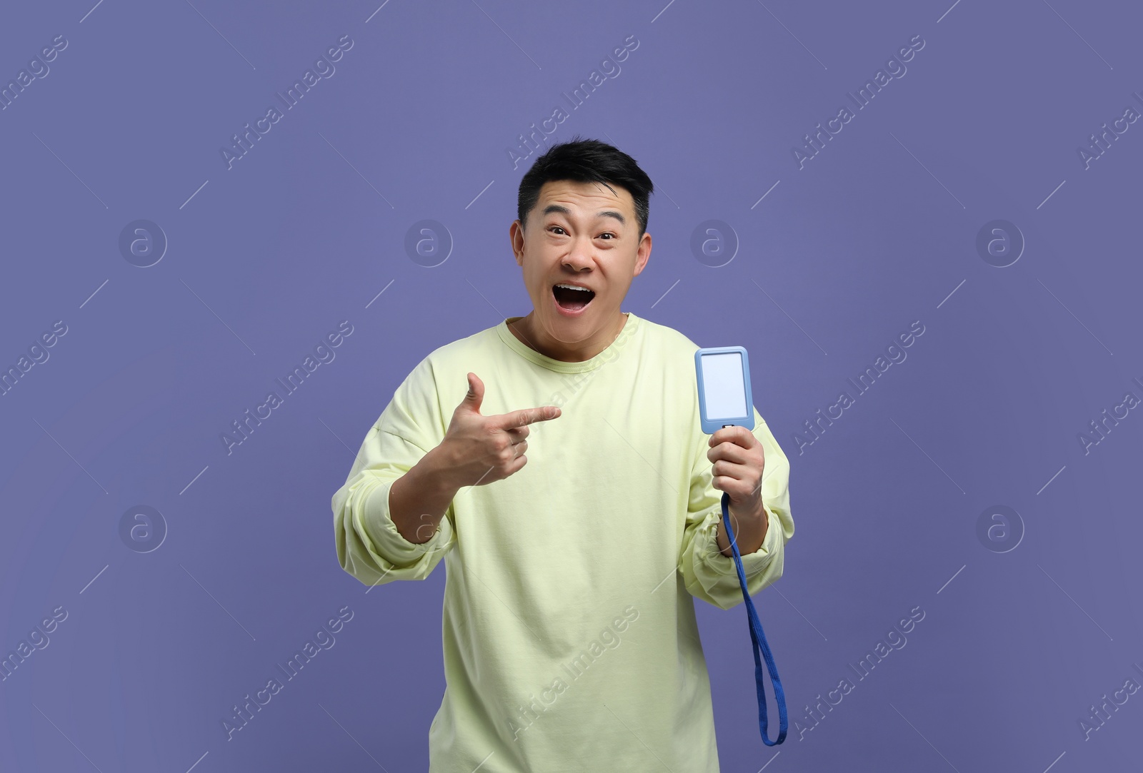 Photo of Emotional asian man with vip pass badge on purple background