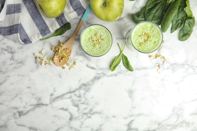 Flat lay composition with green buckwheat smoothie on white marble table, space for text