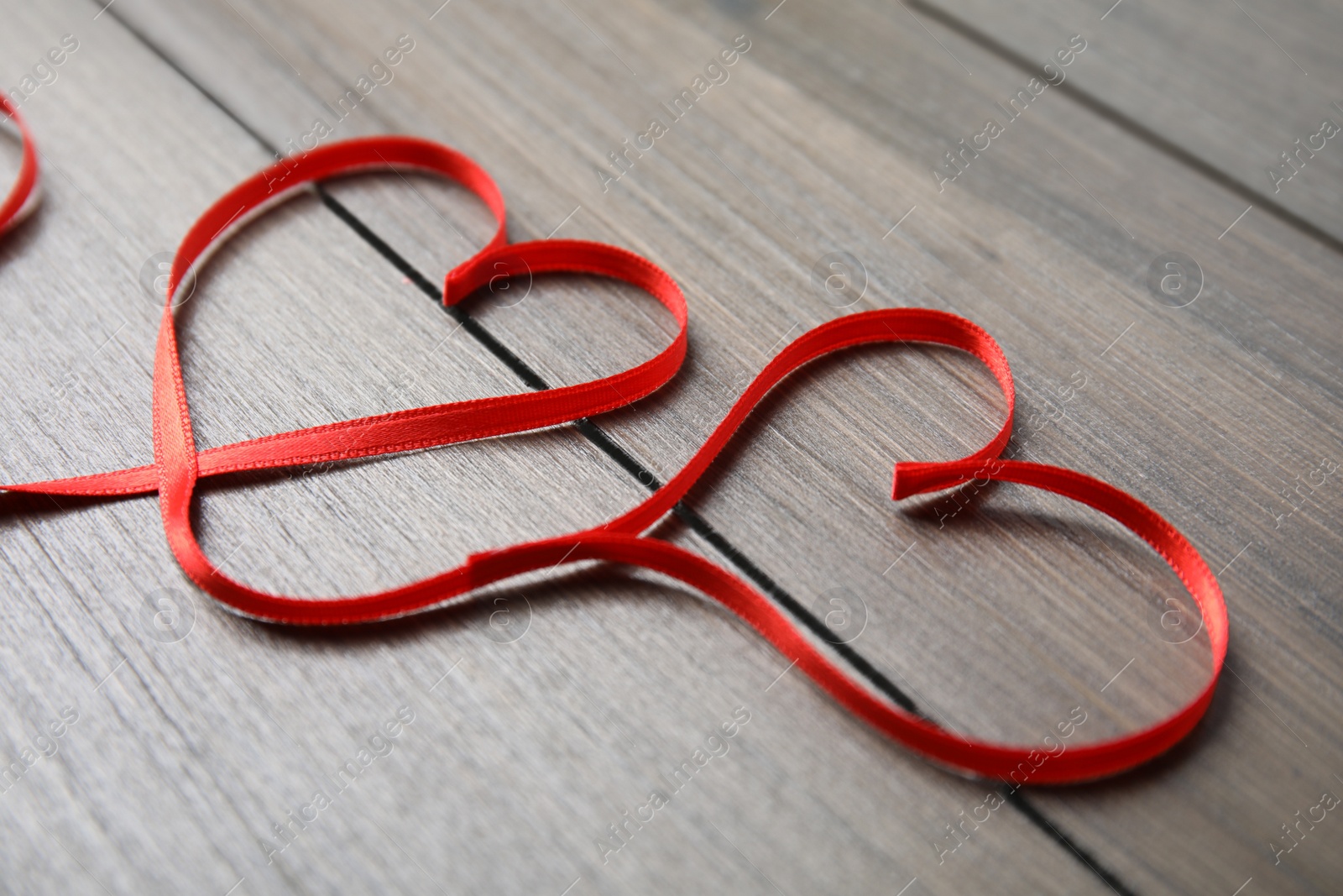 Photo of Hearts made of red ribbon on wooden background. Valentine's day celebration