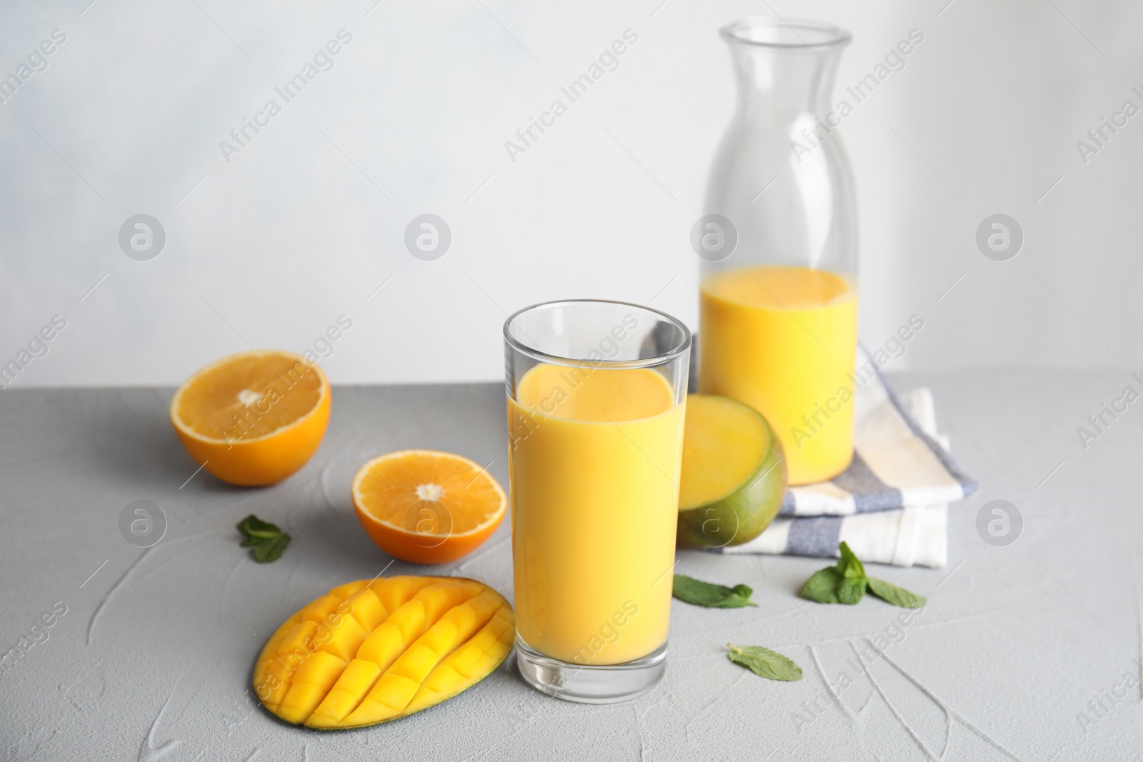 Photo of Fresh mango drink and tropical fruits on table against color background. Space for text