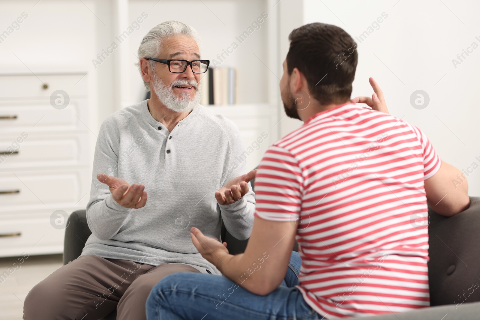 Photo of Happy son and his dad talking at home