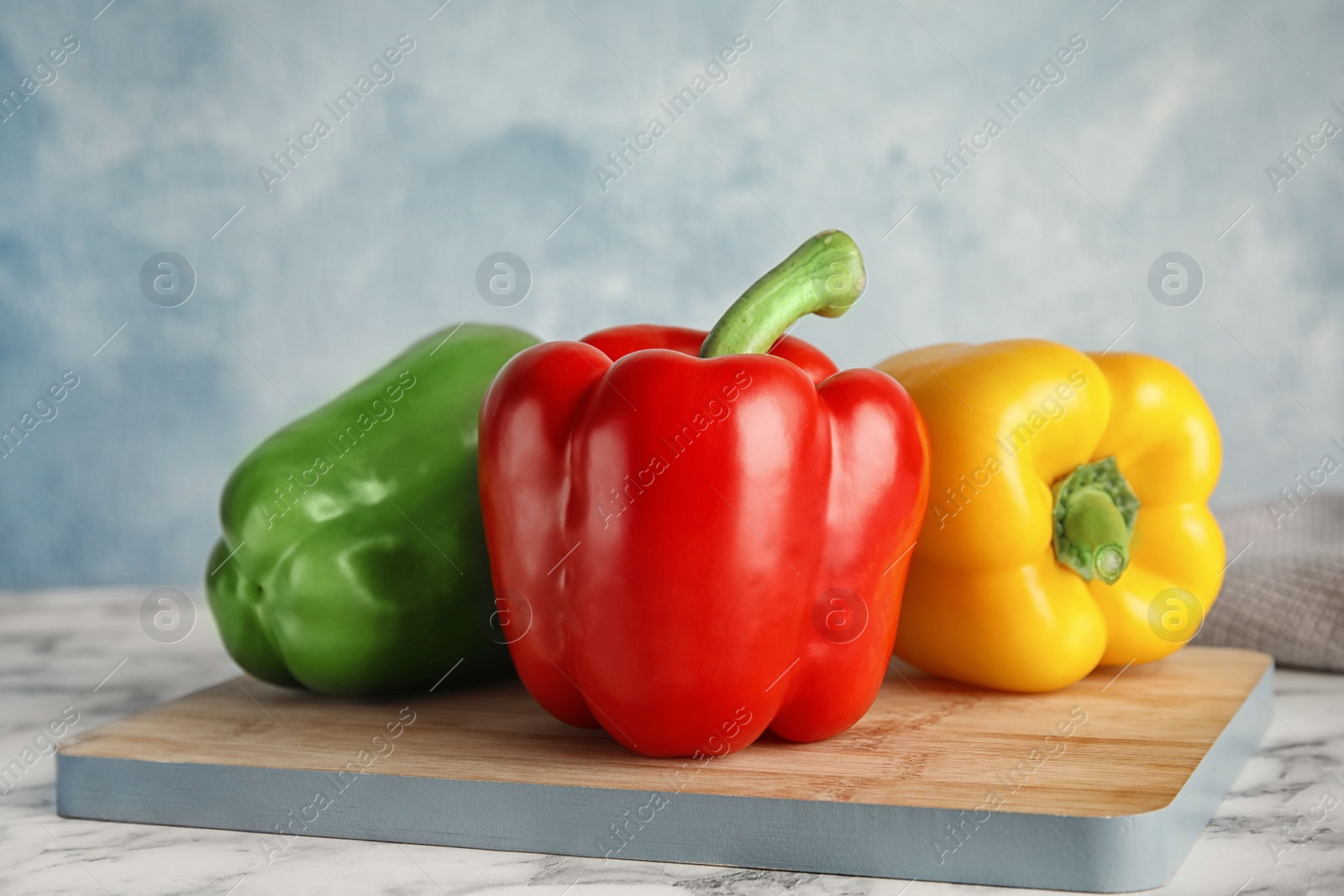 Photo of Wooden board with ripe paprika peppers on table