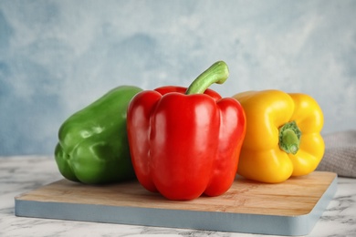 Wooden board with ripe paprika peppers on table