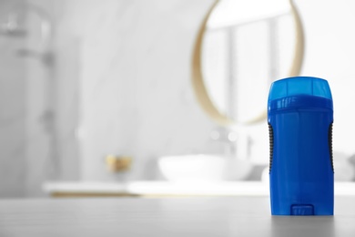 Photo of Deodorant container on table in bathroom. Space for text