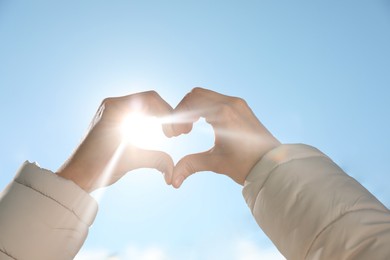 Photo of Woman showing heart against blue sky outdoors on sunny day, closeuphands