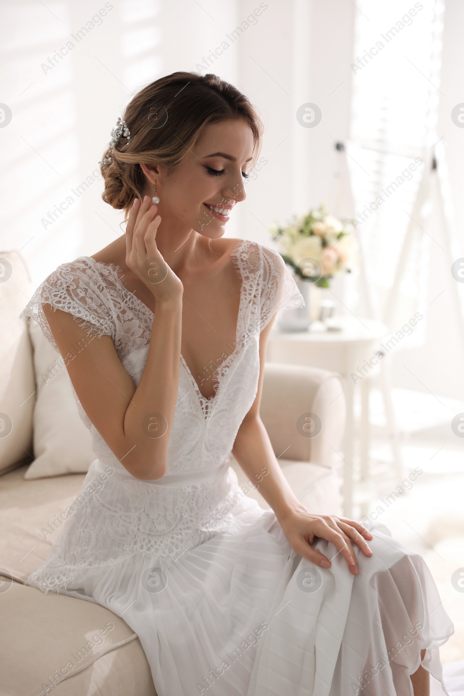 Photo of Gorgeous bride in beautiful wedding dress on sofa in room