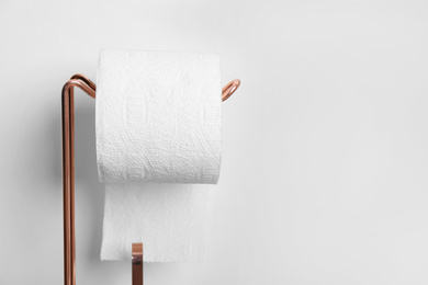 Photo of Toilet paper holder with roll near light wall. Space for text