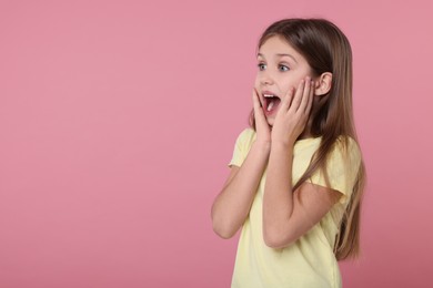Portrait of surprised girl on pink background. Space for text