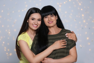 Portrait of young woman and her mature mother against defocused lights