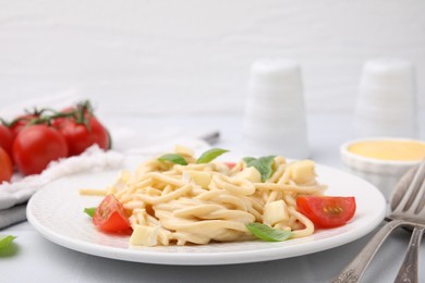 Photo of Delicious pasta with brie cheese, tomatoes and basil leaves on white table, closeup