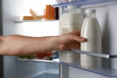 Photo of Man taking gallon of milk from refrigerator, closeup