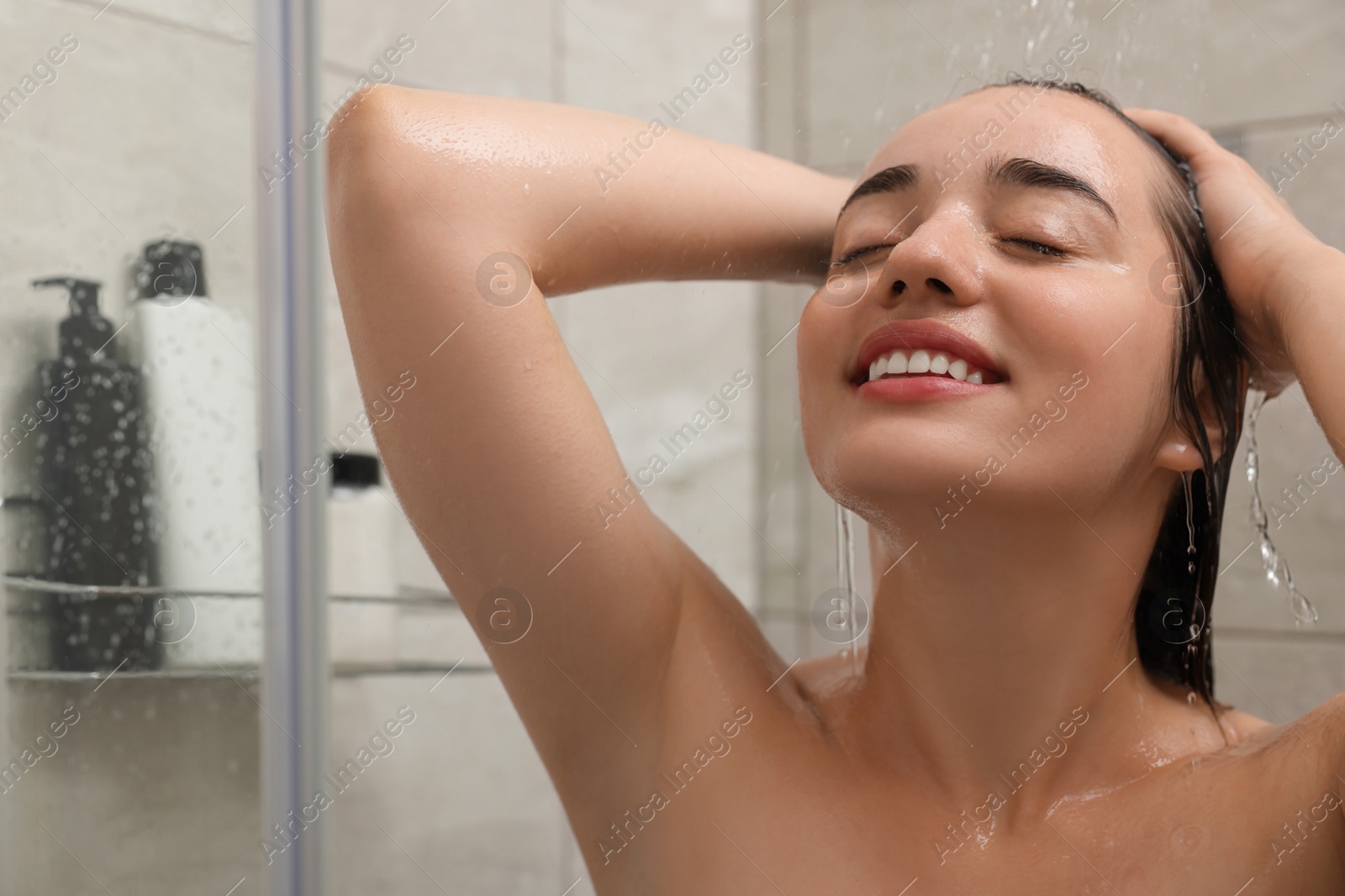 Photo of Happy woman washing hair in shower stall