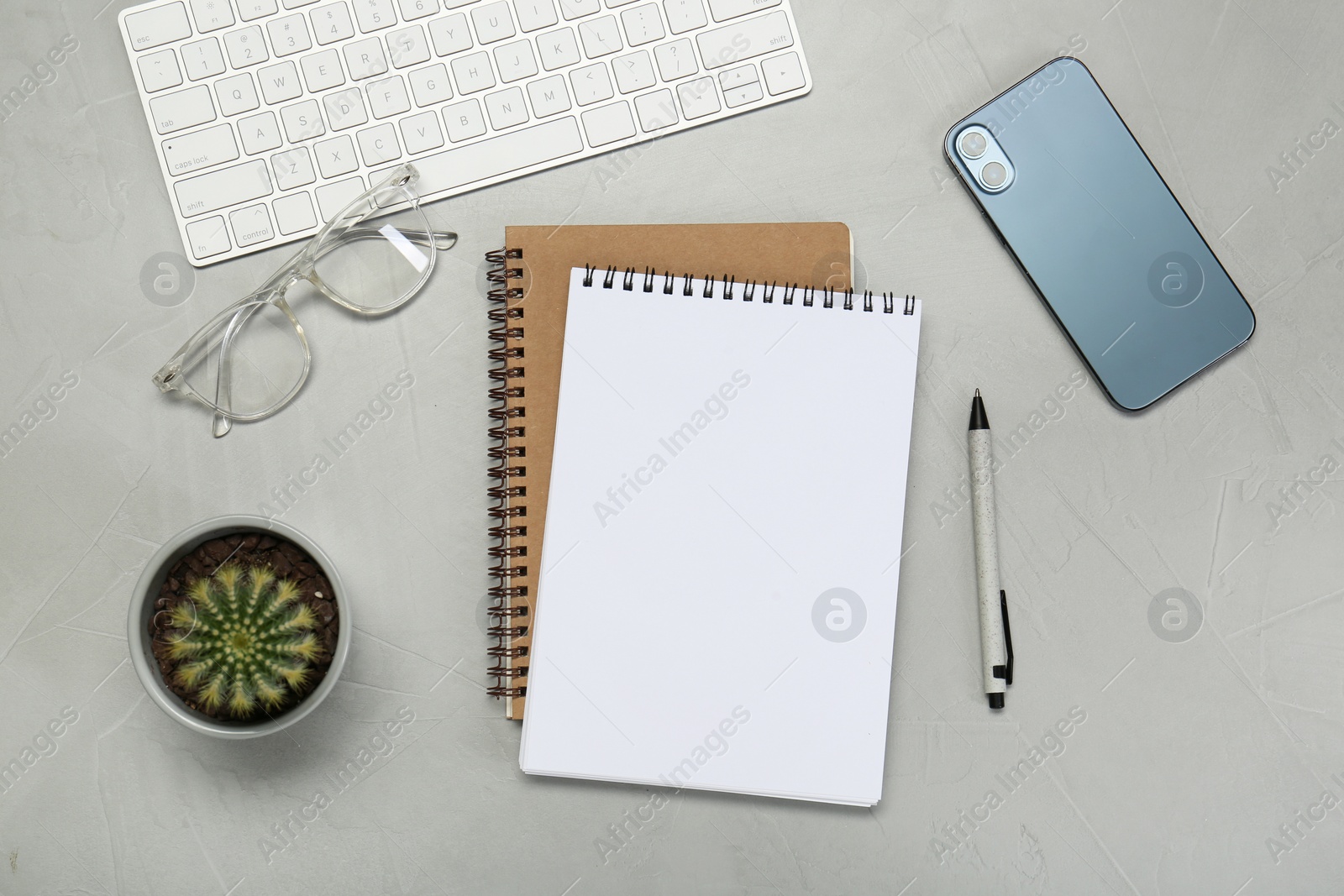 Photo of Flat lay composition with notebooks, smartphone, glasses and pen on light grey table