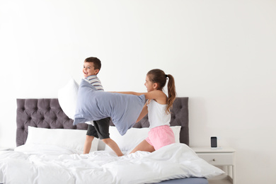 Happy children having pillow fight in bedroom