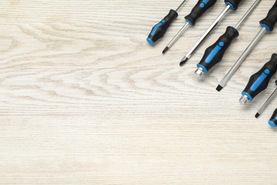 Photo of Set of screwdrivers on white wooden table, top view. Space for text