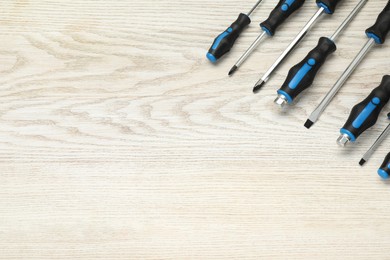 Set of screwdrivers on white wooden table, top view. Space for text