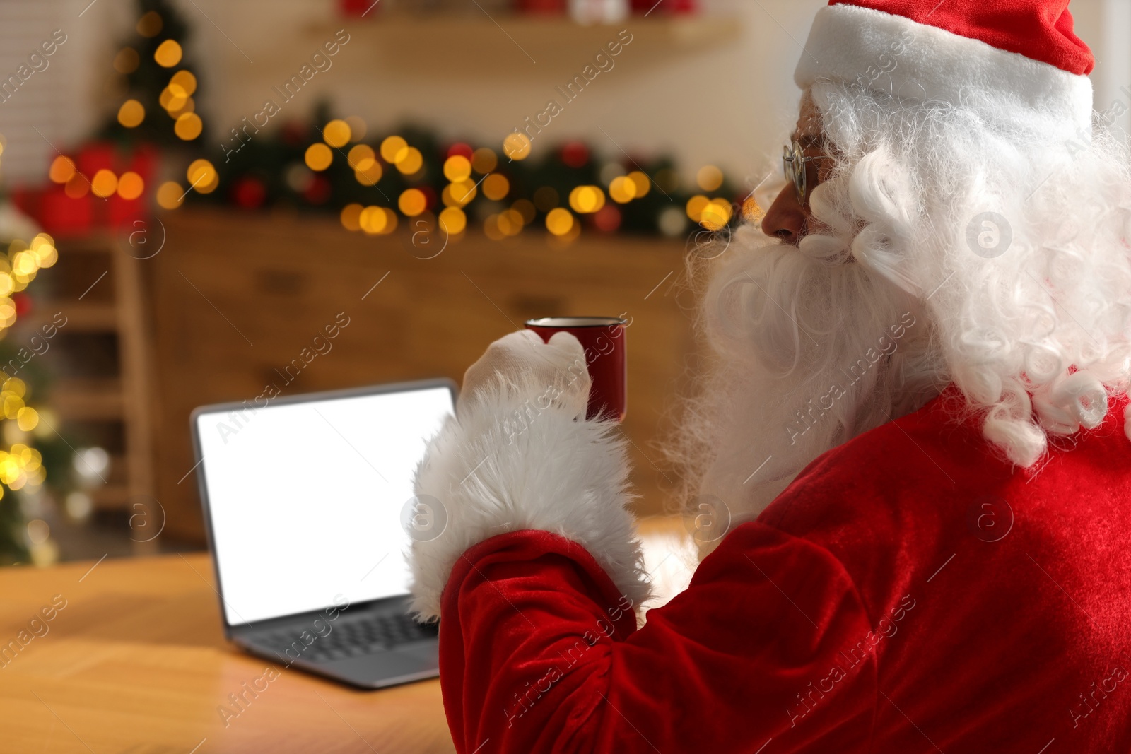 Photo of Merry Christmas. Santa Claus with cup of drink using laptop, closeup