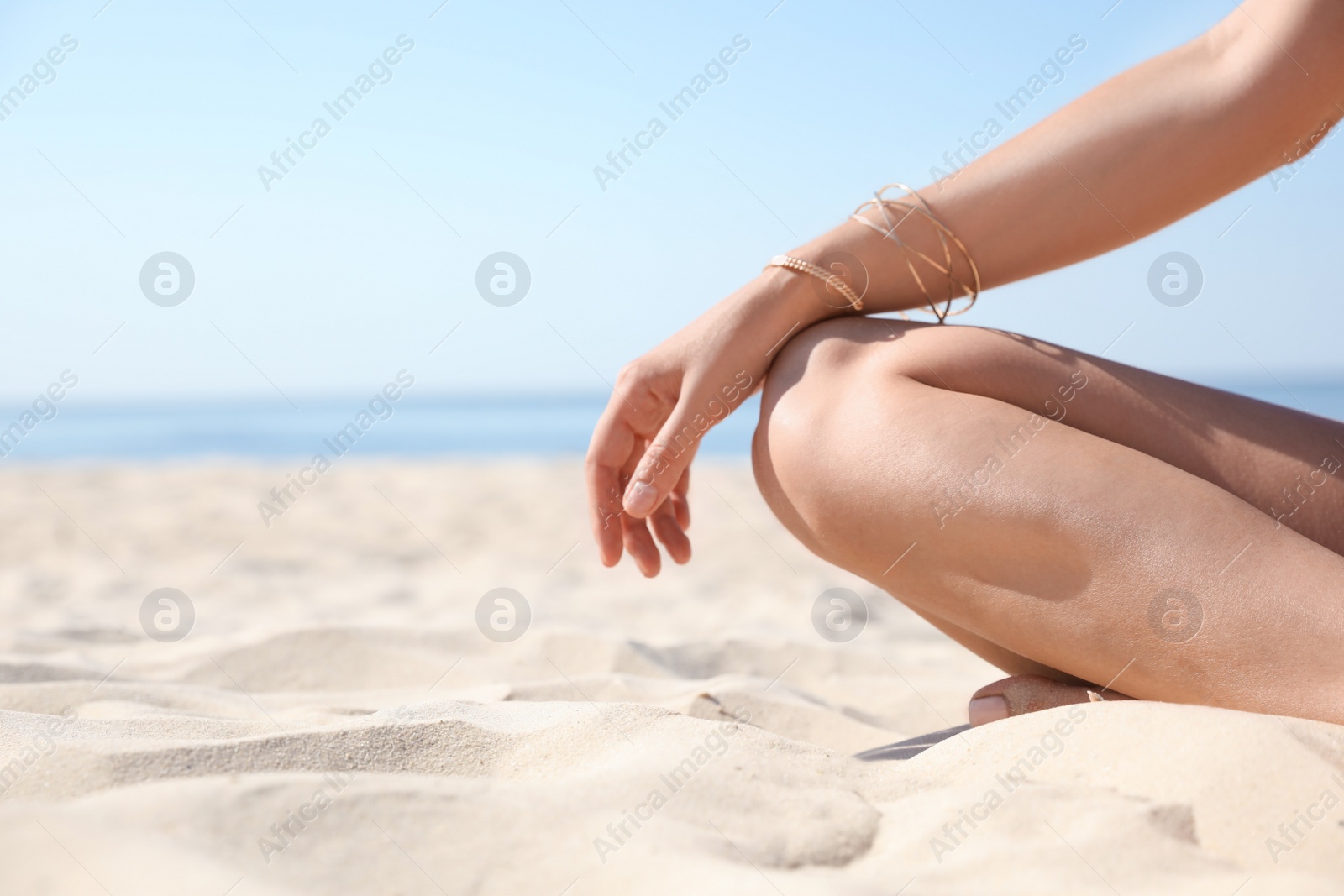 Photo of Young woman with beautiful body on sandy beach, closeup. Space for text