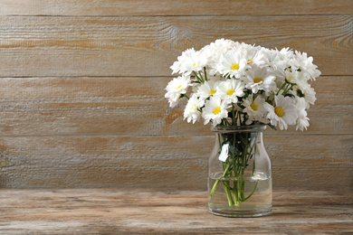 Beautiful white chrysanthemum flowers in glass vase on table. Space for text