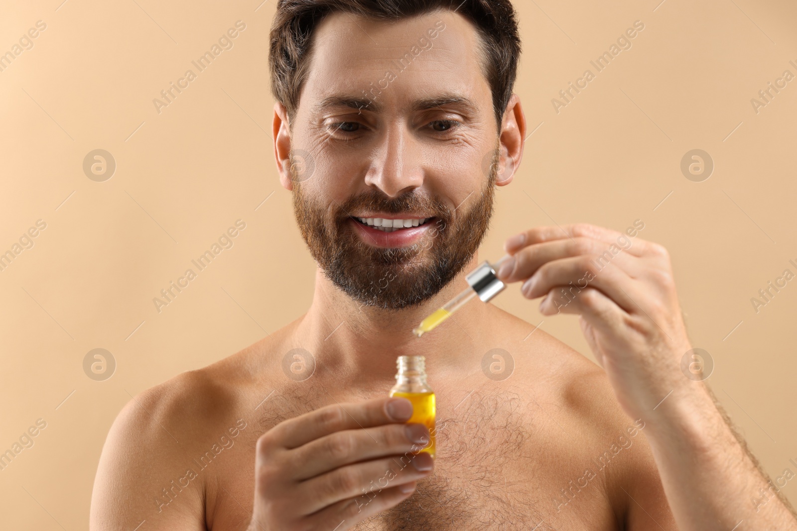 Photo of Smiling man with cosmetic serum on beige background, closeup