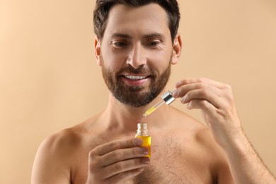 Smiling man with cosmetic serum on beige background, closeup