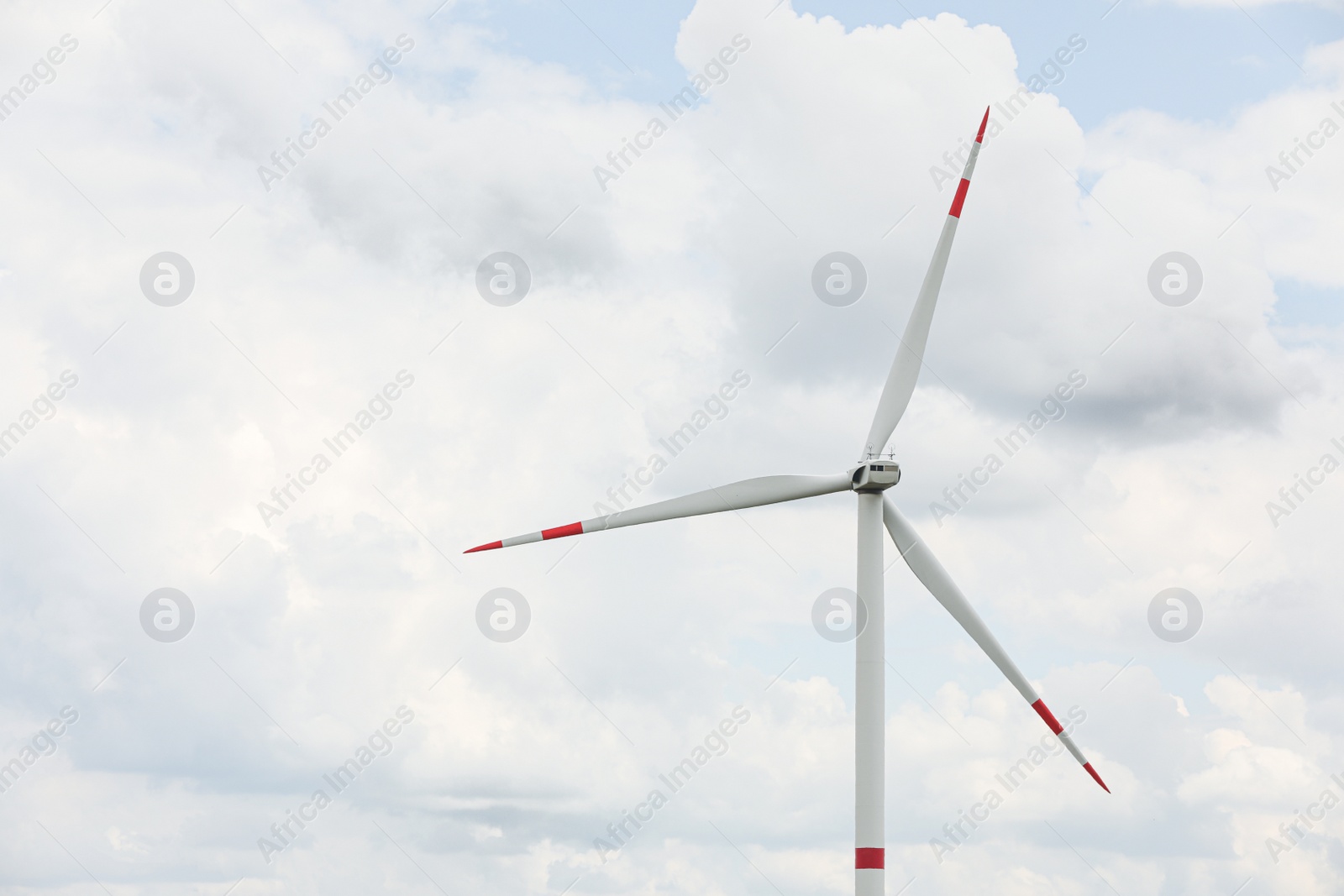 Photo of Modern wind turbine against cloudy sky, closeup. Alternative energy source