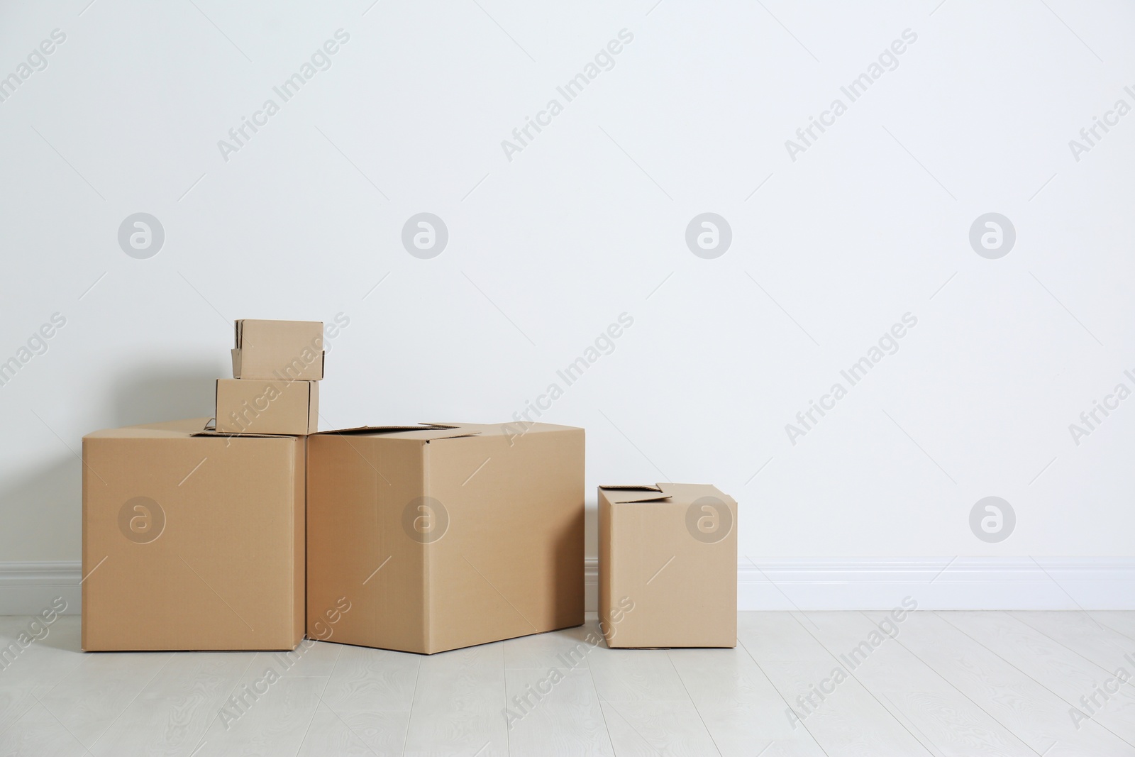 Photo of Cardboard boxes on floor near white wall