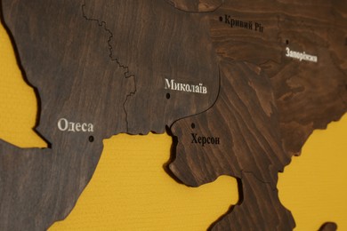 Wooden map of southern Ukraine with city names in Ukrainian on yellow background, closeup