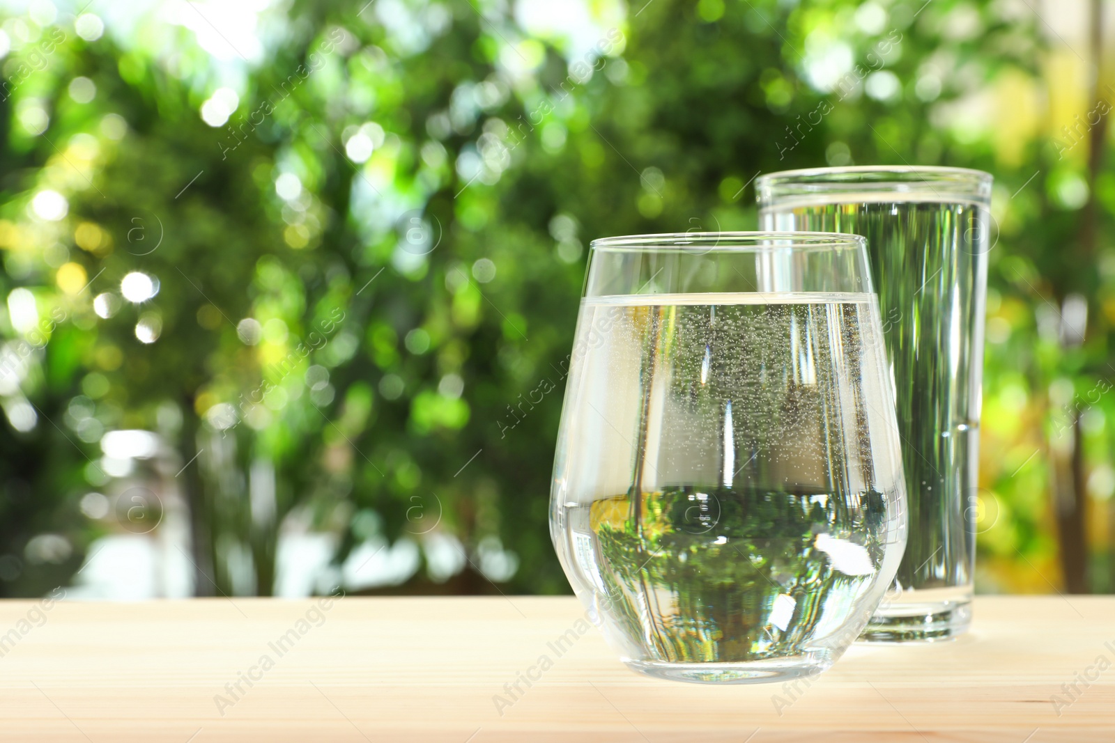 Photo of Glasses of water on table against blurred background, space for text. Refreshing drink