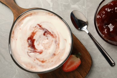 Photo of Tasty yoghurt with jam and strawberry on grey table, flat lay