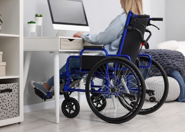 Photo of Woman in wheelchair using computer at home, closeup