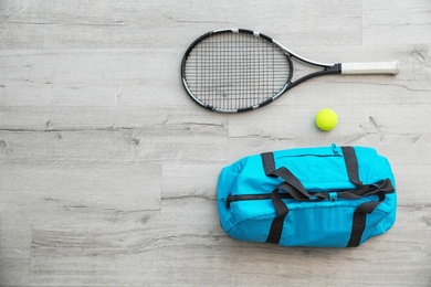 Sports bag, racket and ball on wooden floor, top view