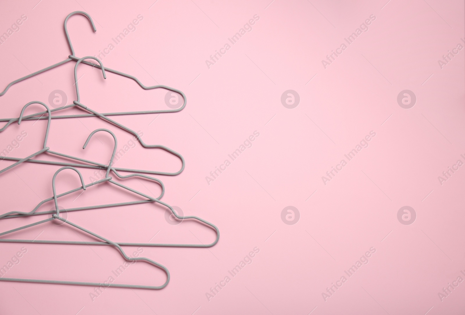 Photo of Hangers on pink background, flat lay. Space for text