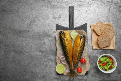 Flat lay composition with tasty smoked fish on grey table. Space for text