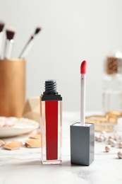 Photo of Liquid lipstick with applicator and cosmetics on table