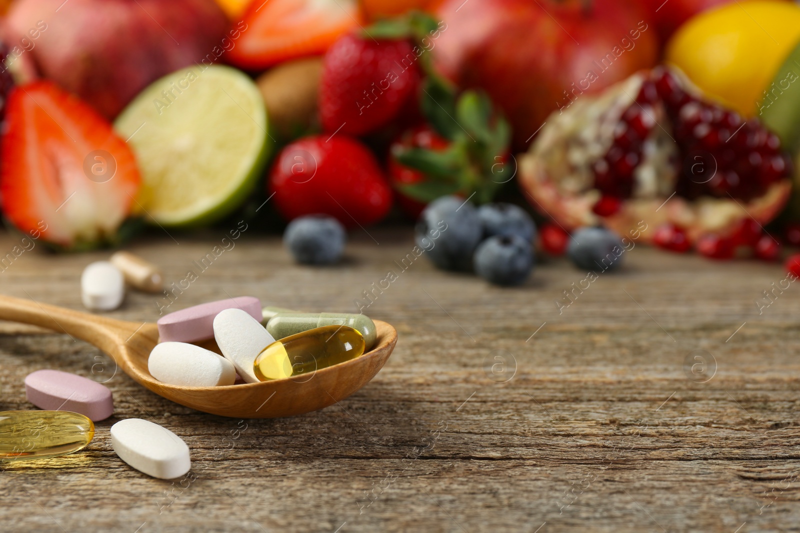 Photo of Different vitamin pills and fresh fruits on wooden table. Space for text