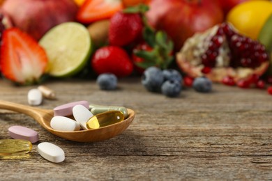 Photo of Different vitamin pills and fresh fruits on wooden table. Space for text