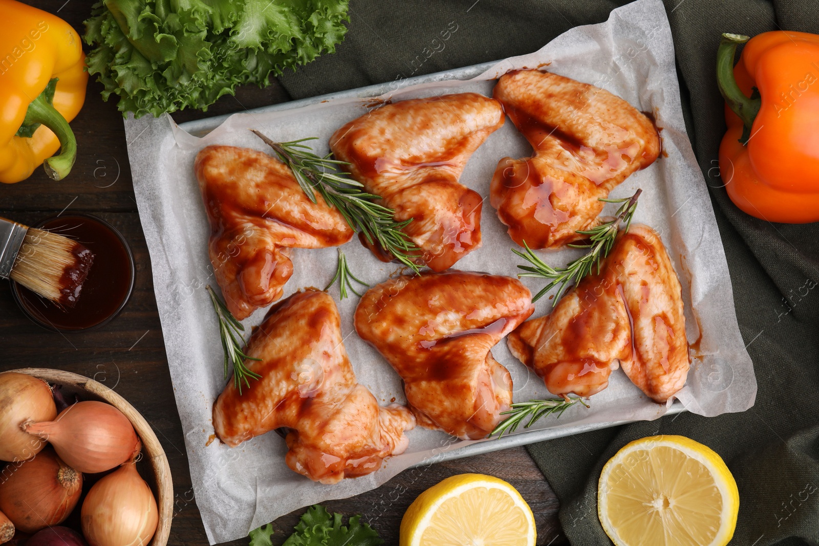 Photo of Flat lay composition with raw marinated chicken wings, rosemary and other products on wooden table