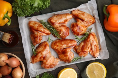 Flat lay composition with raw marinated chicken wings, rosemary and other products on wooden table