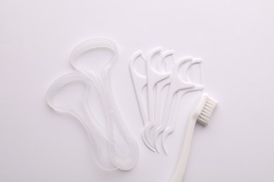 Photo of Tongue cleaners, dental floss picks and toothbrush on white background, top view