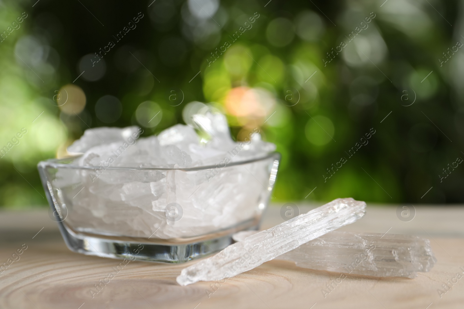 Photo of Menthol crystals on wooden table against blurred background. Space for text