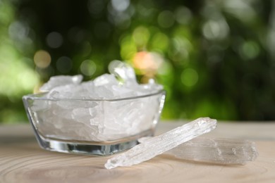 Menthol crystals on wooden table against blurred background. Space for text