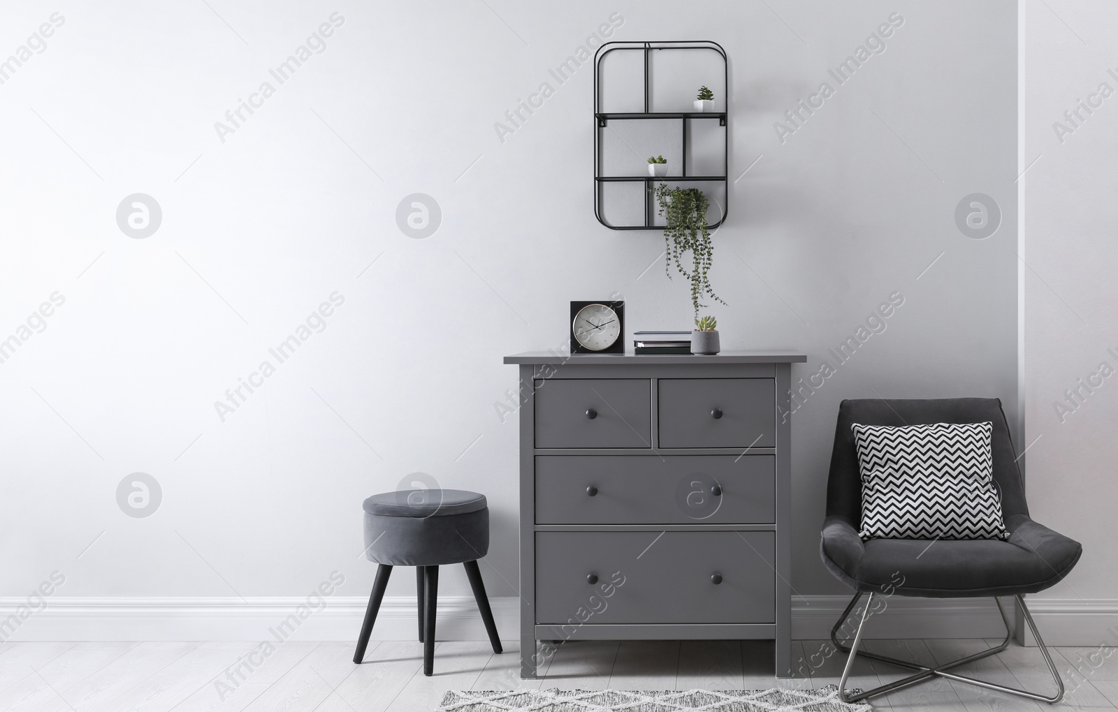 Photo of Elegant room interior with stylish chest of drawers, pouf and comfortable armchair