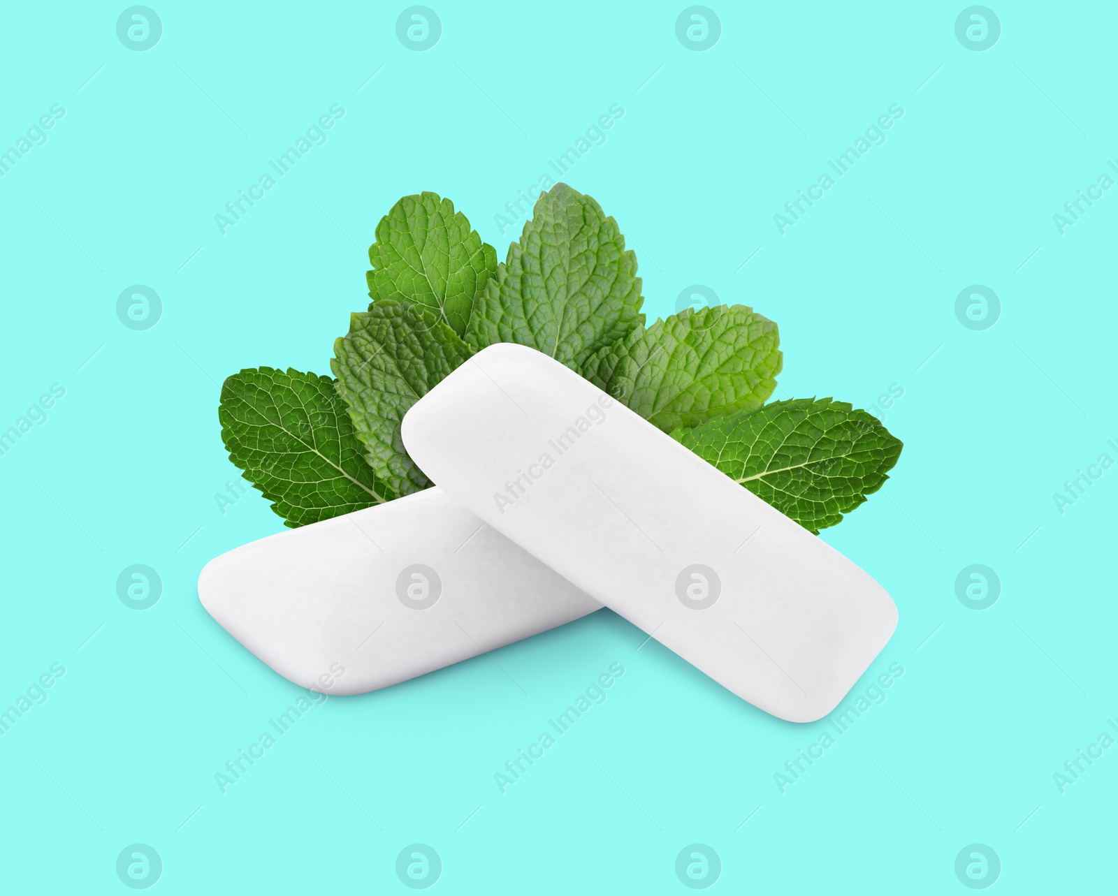 Image of Menthol chewing gum pillows and mint leaves on cyan background