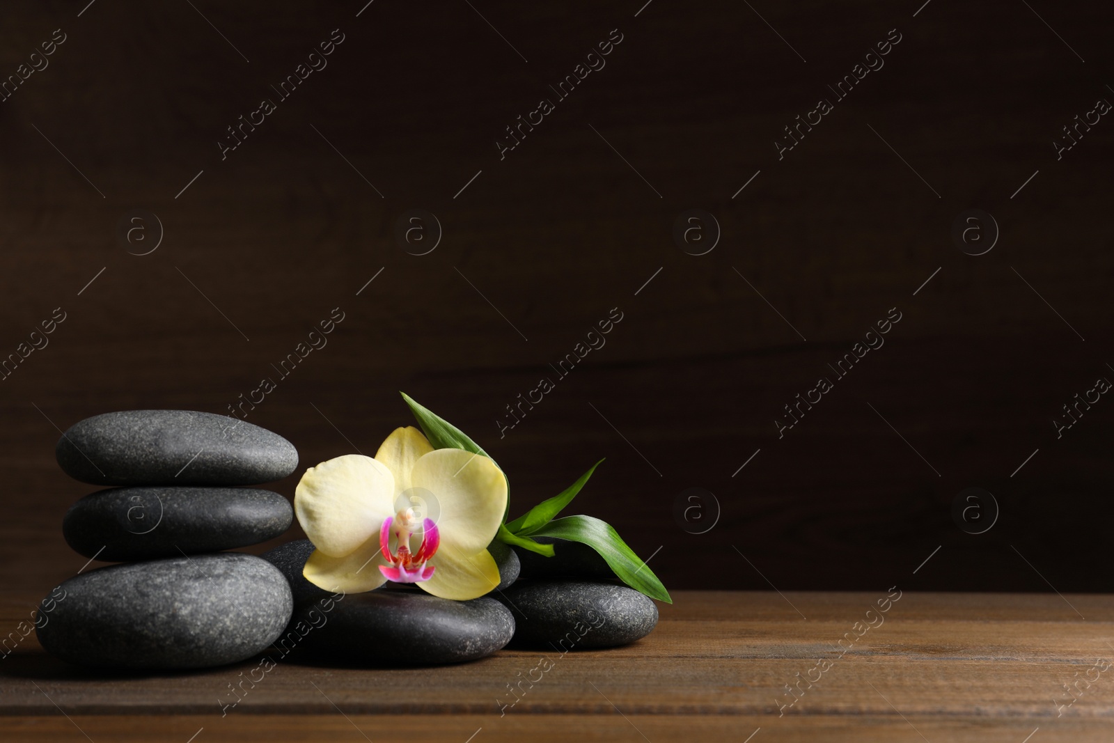 Photo of Spa stones, beautiful orchid flower and bamboo sprout on wooden table. Space for text