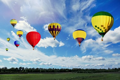 Image of Bright hot air balloons flying over field