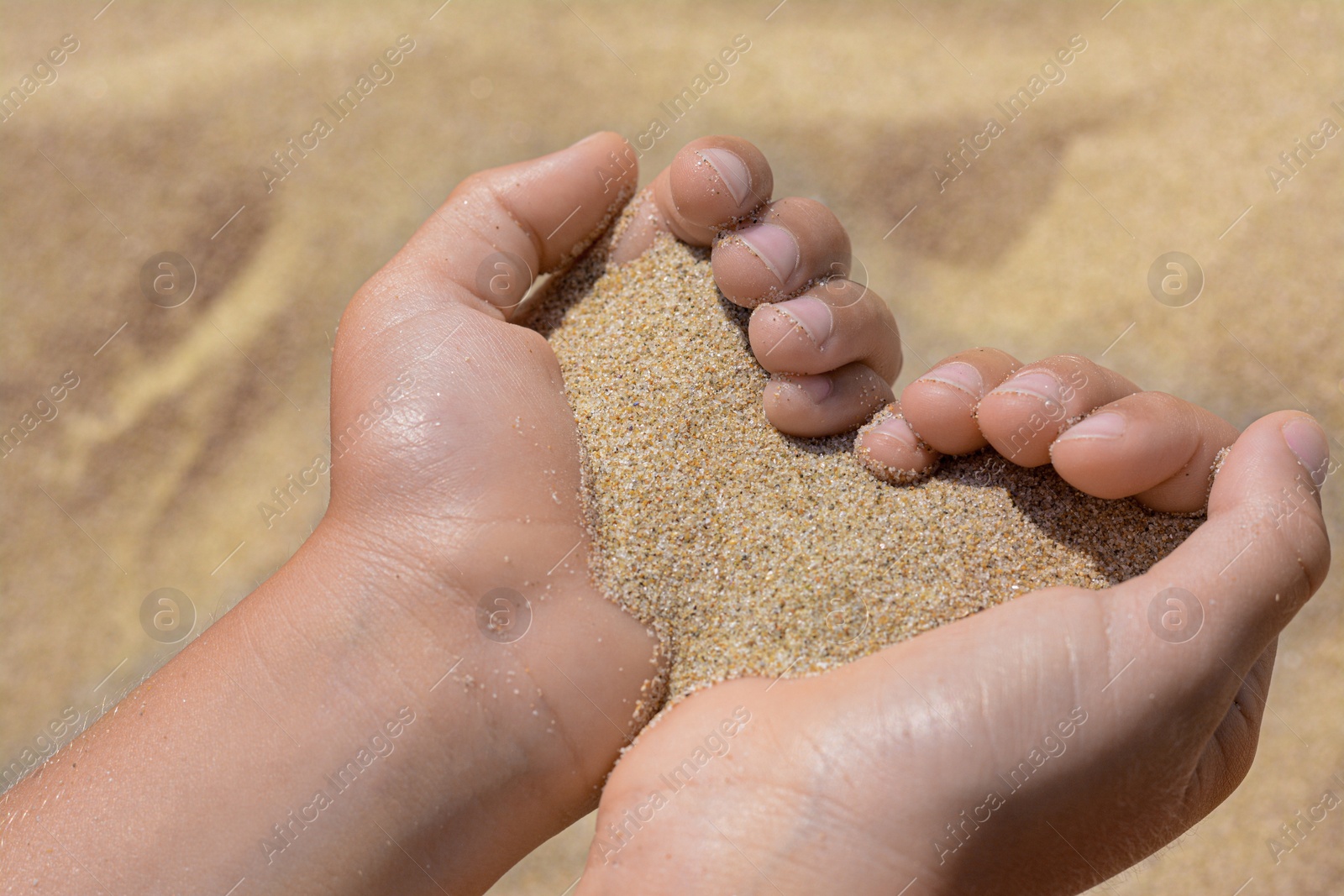 Photo of Child holding sand in hands outdoors, closeup. Fleeting time concept