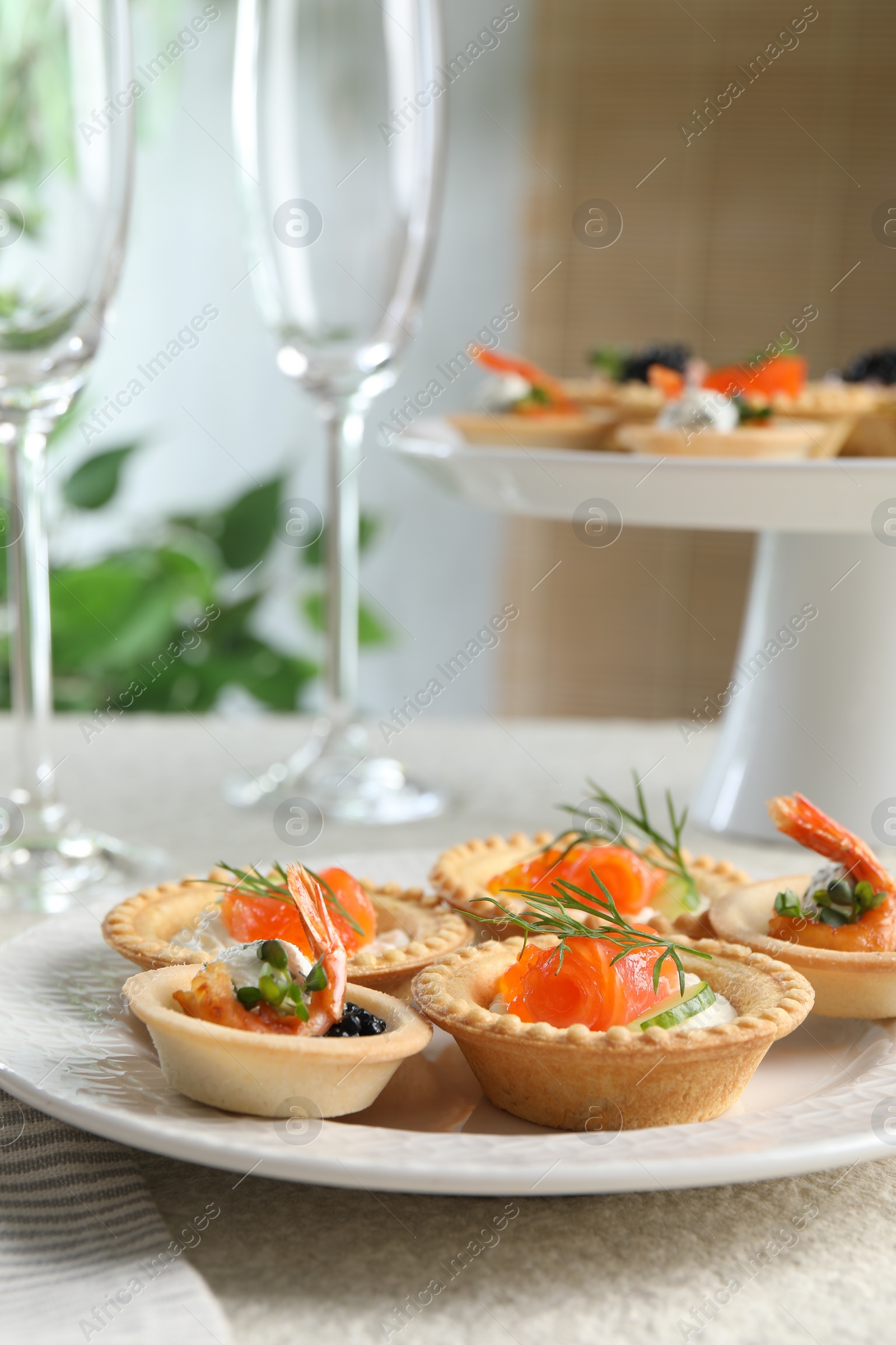 Photo of Delicious canapes with shrimps, salmon and caviar on beige textured table, closeup