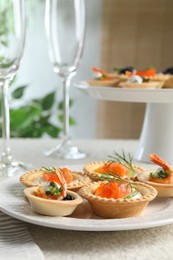 Photo of Delicious canapes with shrimps, salmon and caviar on beige textured table, closeup