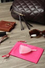 Photo of Menstrual cup and different women's accessories on wooden table